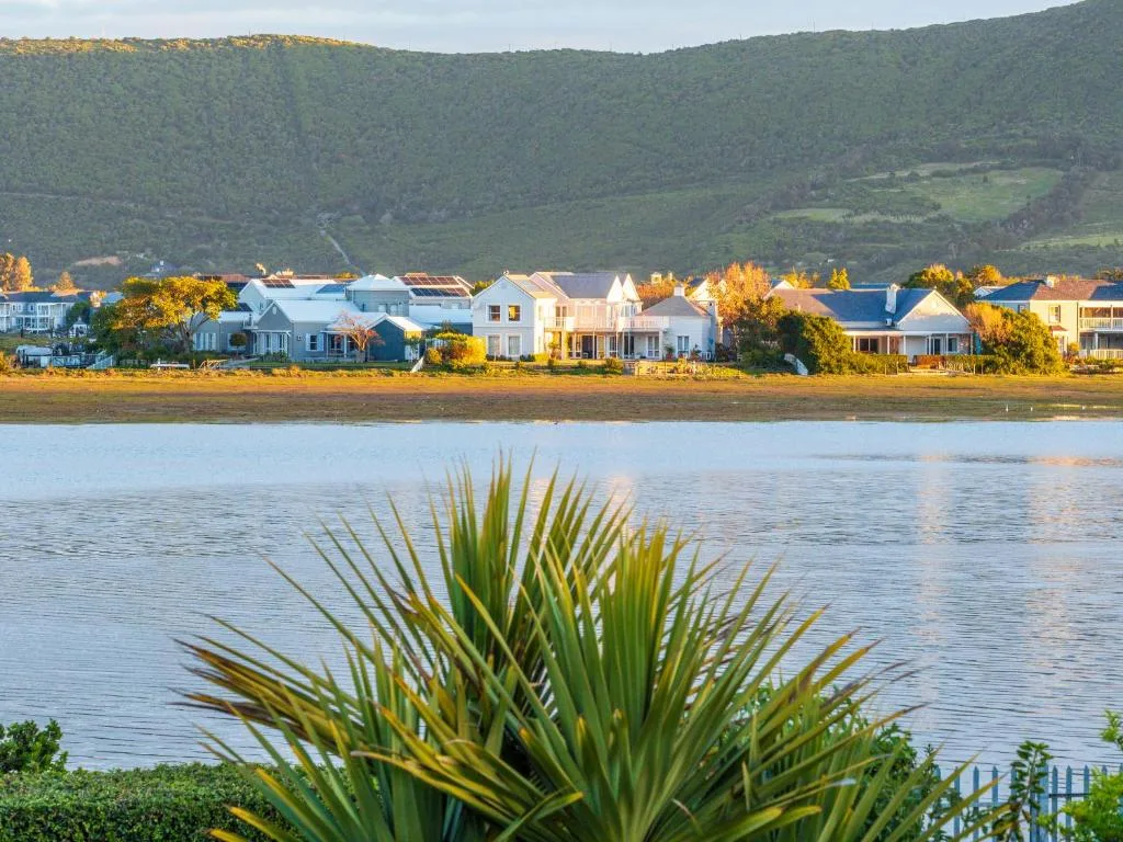 Waterfront homes and forested mountains across calm lagoon waters