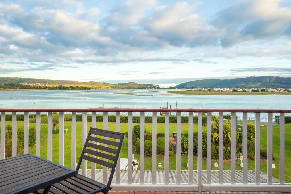 Panoramic lagoon and mountain vista from a waterfront deck railing