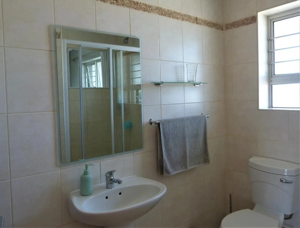 Clean bathroom with vanity sink, mirror, toilet, and towel rack
