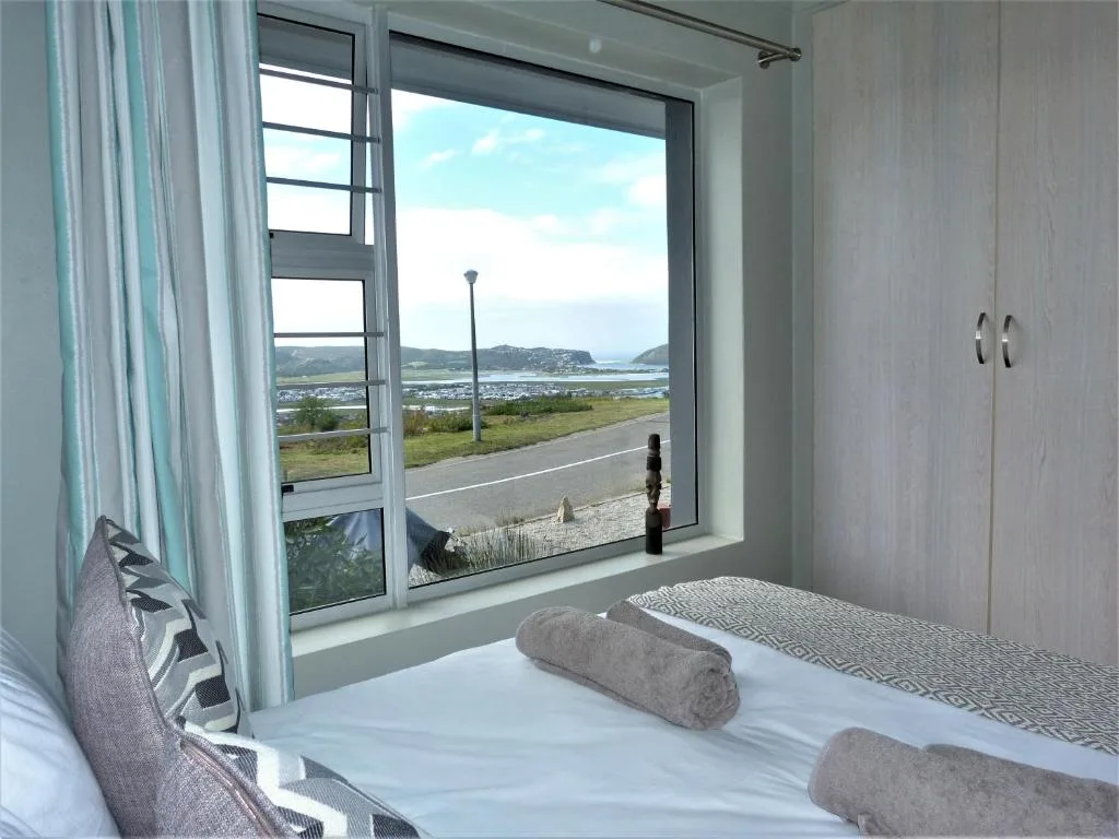 Bedroom with bed and large window overlooking Knysna lagoon and mountains