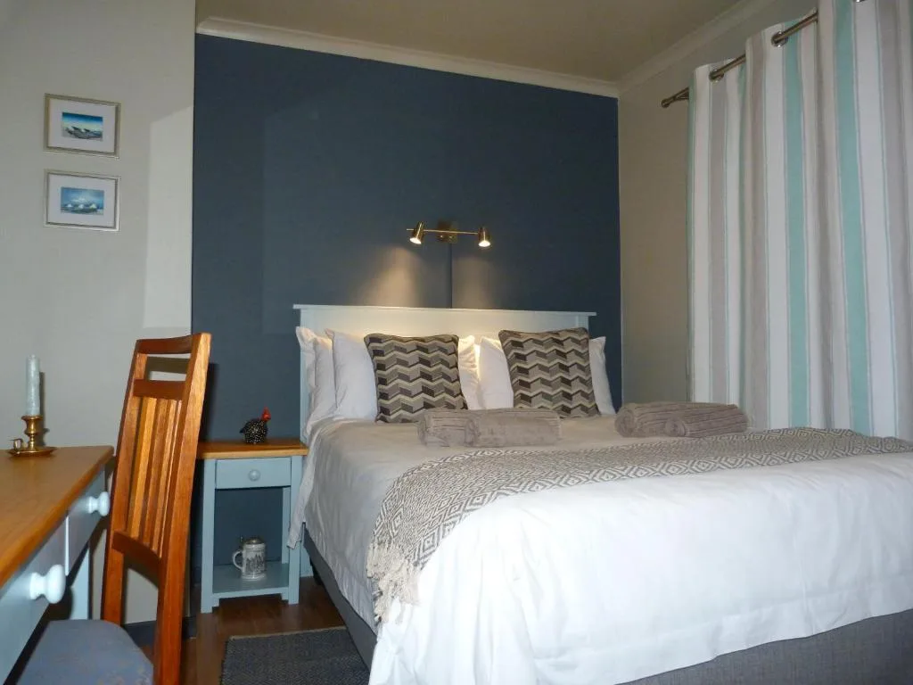 Modern bedroom with queen bed, dark blue accent wall, and contemporary lighting