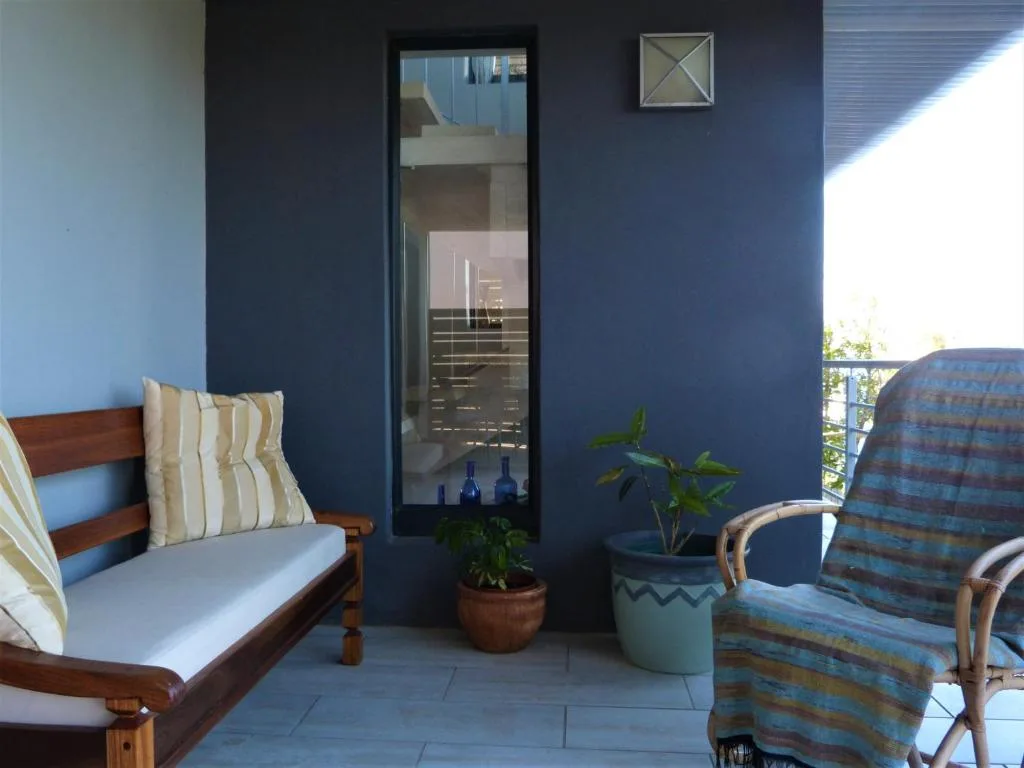 Covered patio with wooden chairs, potted plants, and blue feature wall