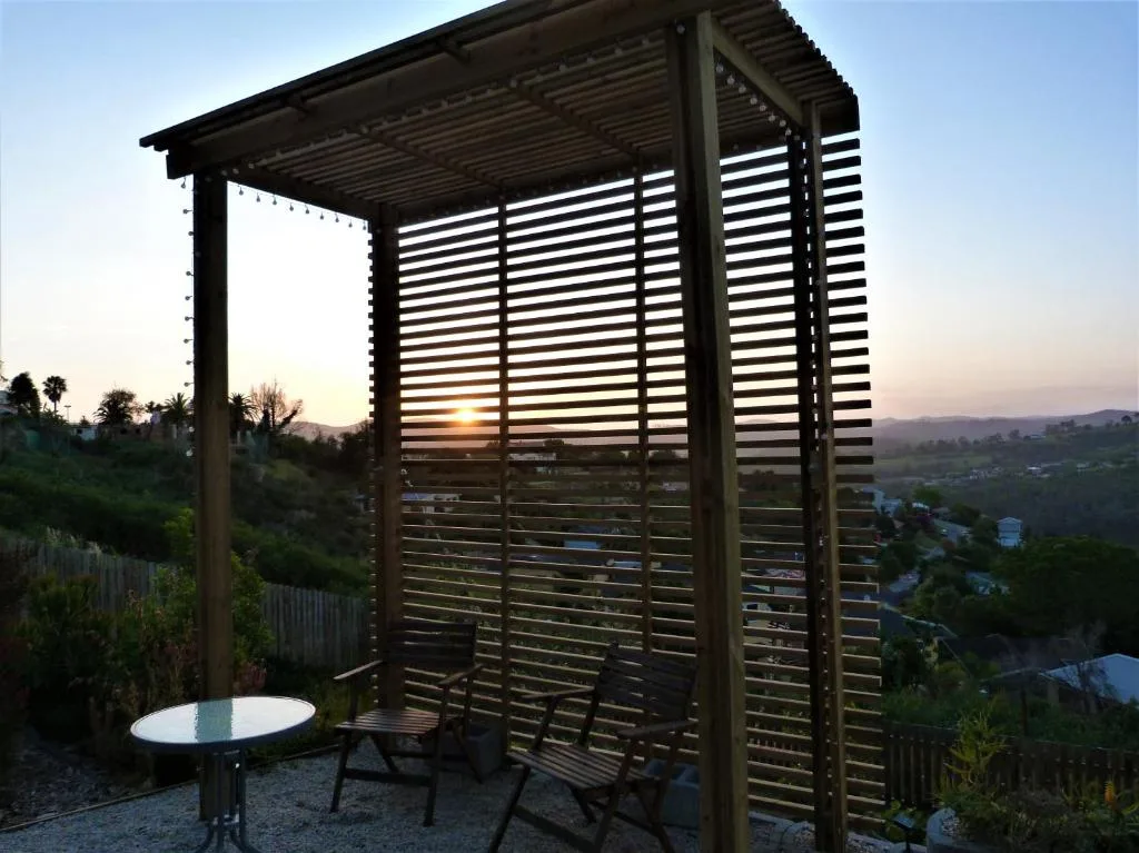 Modern pergola with louvered shade overlooking valley at sunset