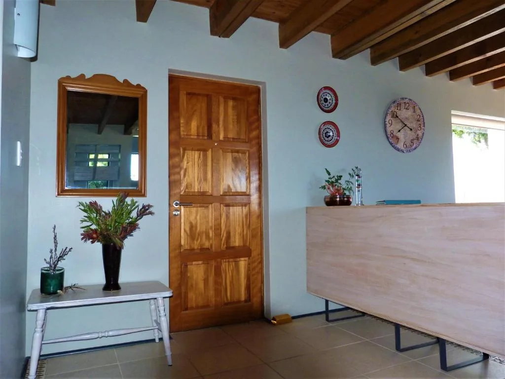 Interior entryway with wooden door, mirror, decorative clocks, and potted plants