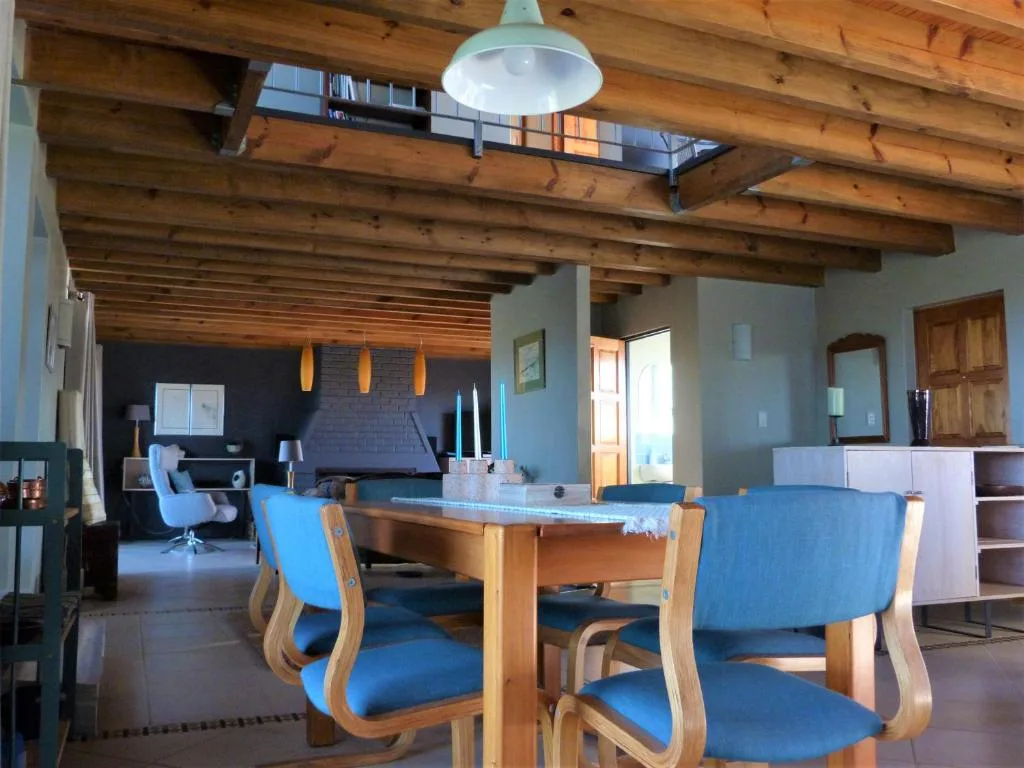 Open-plan dining area with wooden table and blue chairs, exposed beams