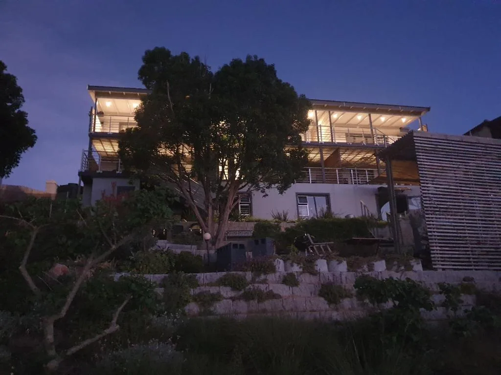 Modern two-story white house illuminated at dusk with landscaped garden