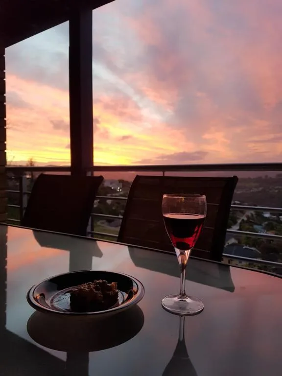 Sunset over lagoon with wine glass and food on railing