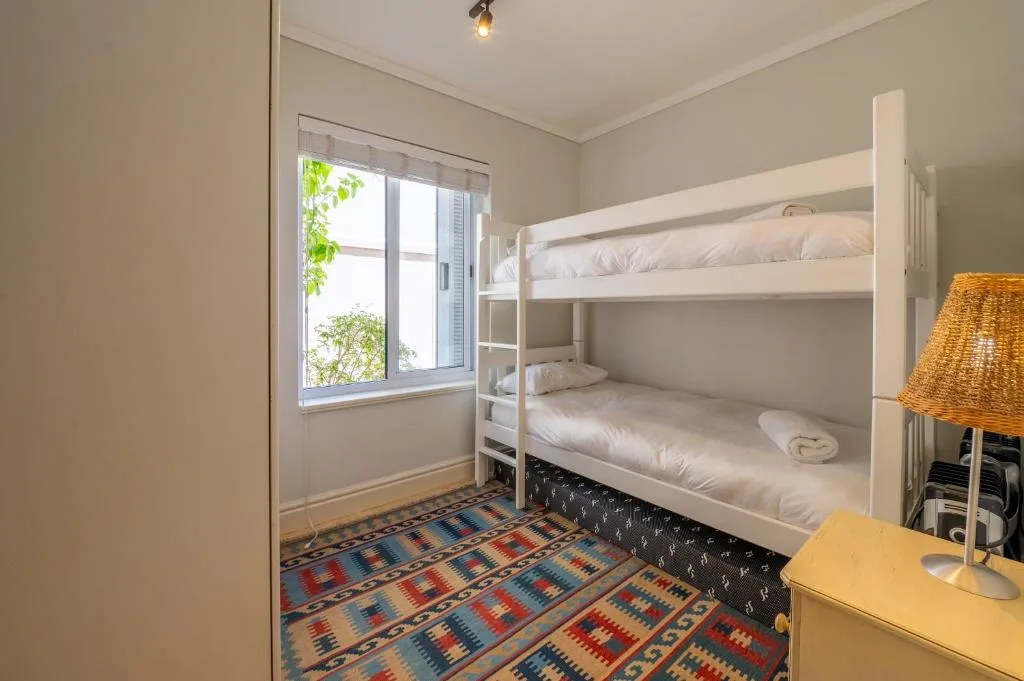 Bright bedroom with white bunk beds and colorful patterned rug