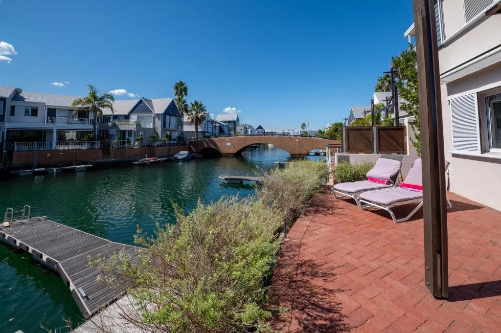 Waterfront patio with loungers overlooking canal and moored boats