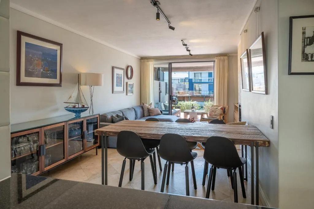 Open-plan dining area with wooden table and black chairs overlooking lounge