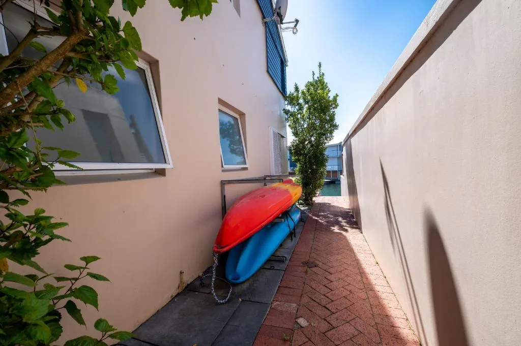 Narrow side passage with kayaks stored against cream-colored building wall