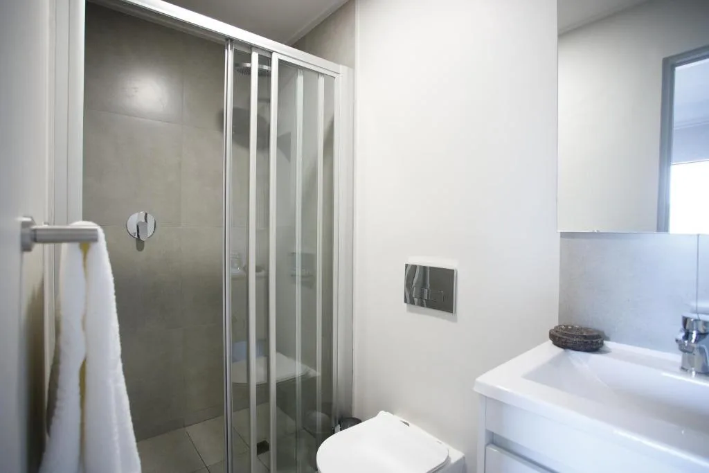 Modern bathroom with shower enclosure, white sink, and toilet