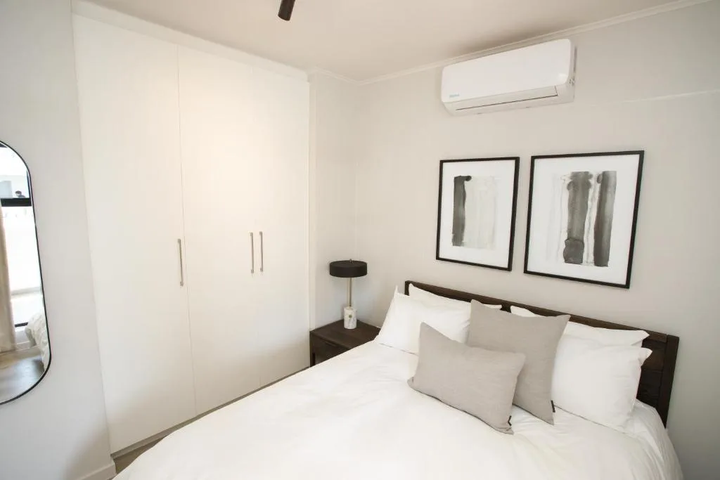 Modern bedroom with queen bed, white bedding, dark wood frame, built-in wardrobe