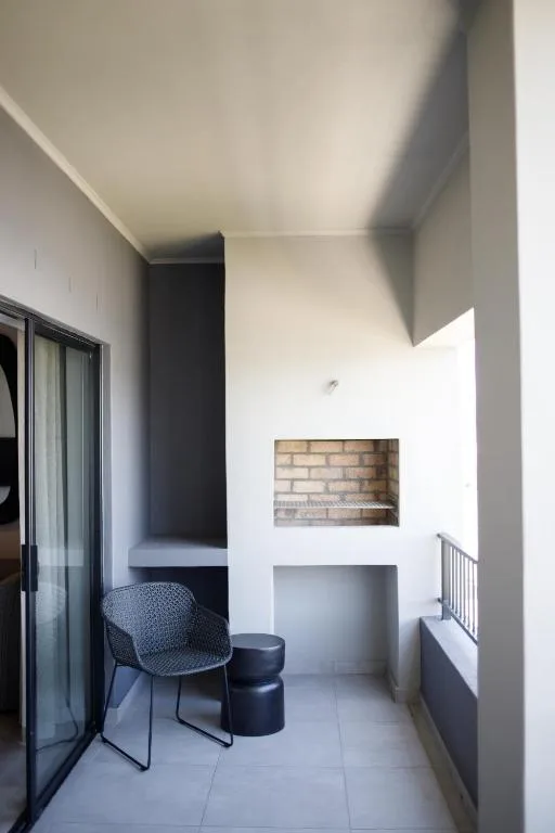 Modern covered outdoor seating area with chair, ottoman, and brick fireplace feature