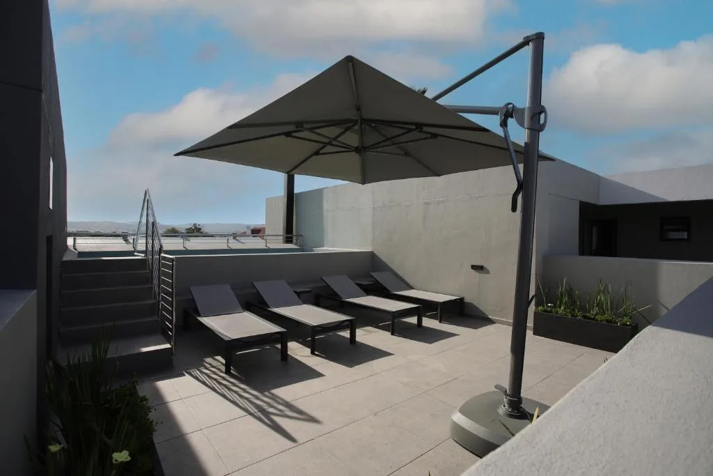 Rooftop terrace with loungers, black cantilever umbrella, and mountain views