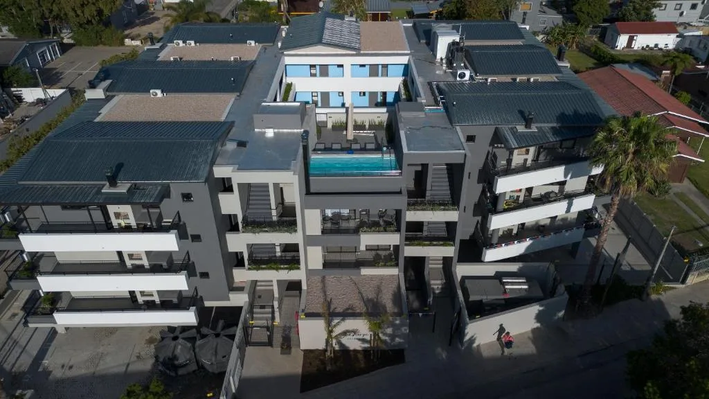 Modern multi-story apartment building with rooftop pool and surrounding neighborhood