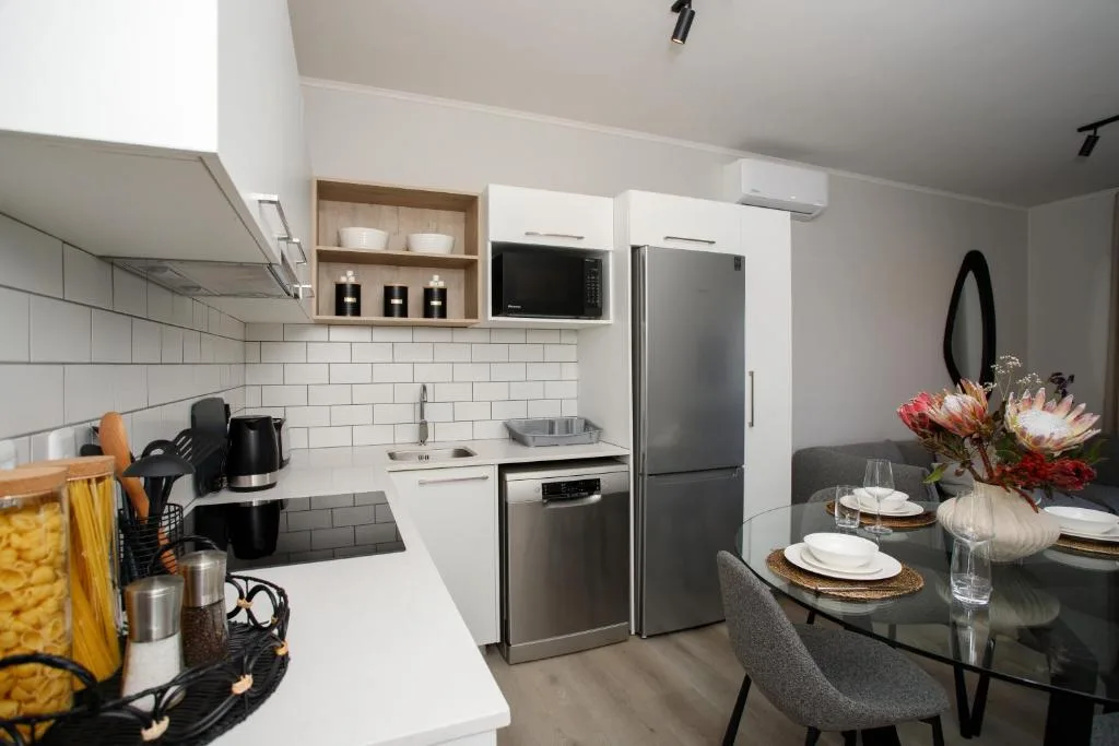 Modern kitchen with stainless steel appliances, white cabinetry, and dining area