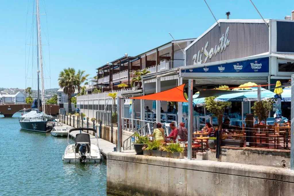 Waterfront marina with sailboats and bustling harbor restaurant area