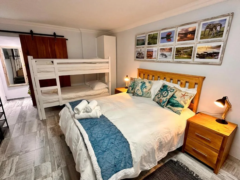 Bright bedroom with double bed, bunk bed, and coastal-themed wall art