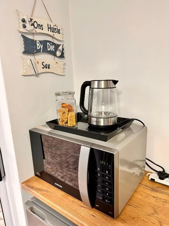 Microwave with kettle and coffee setup on wooden shelf