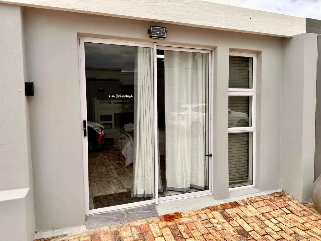 Modern white apartment entrance with sliding glass doors and brick patio