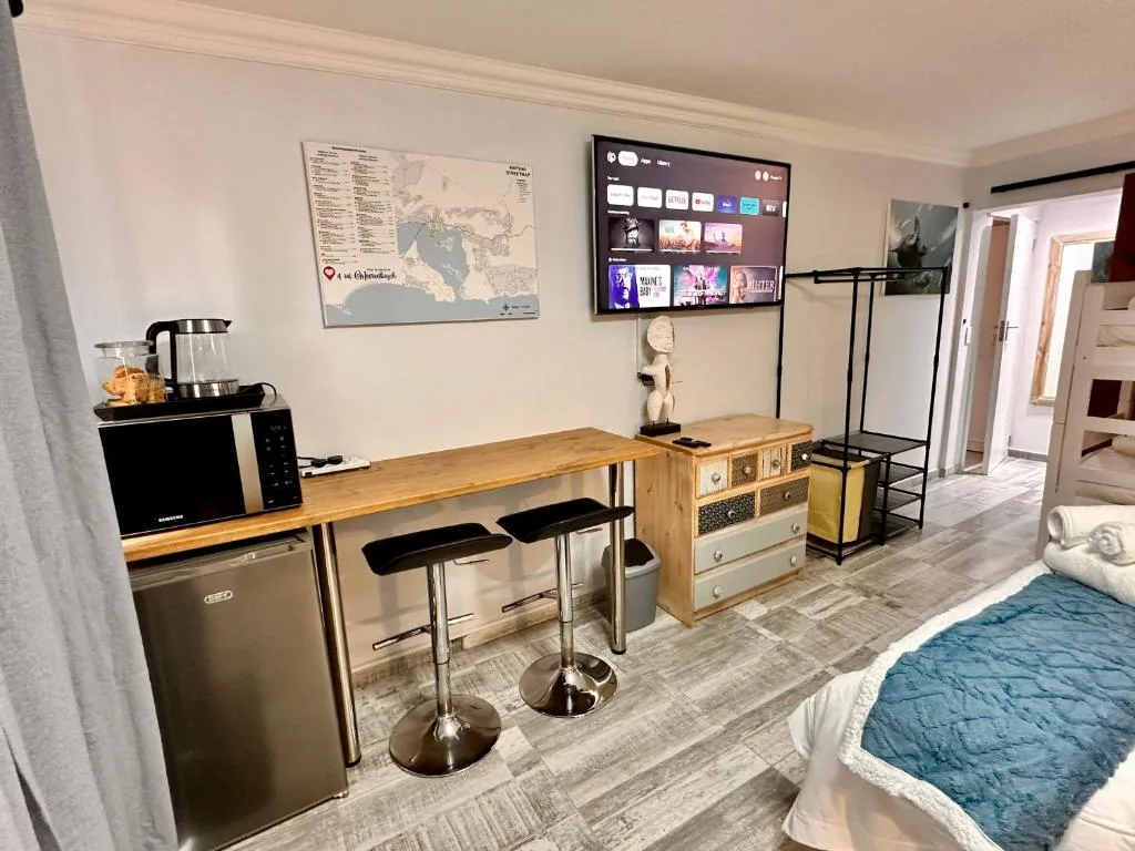 Open-plan lounge with smart TV, wooden counter seating, and kitchenette area