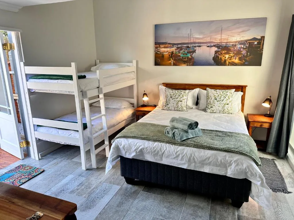 Spacious bedroom with double bed, bunk beds, and harbor artwork