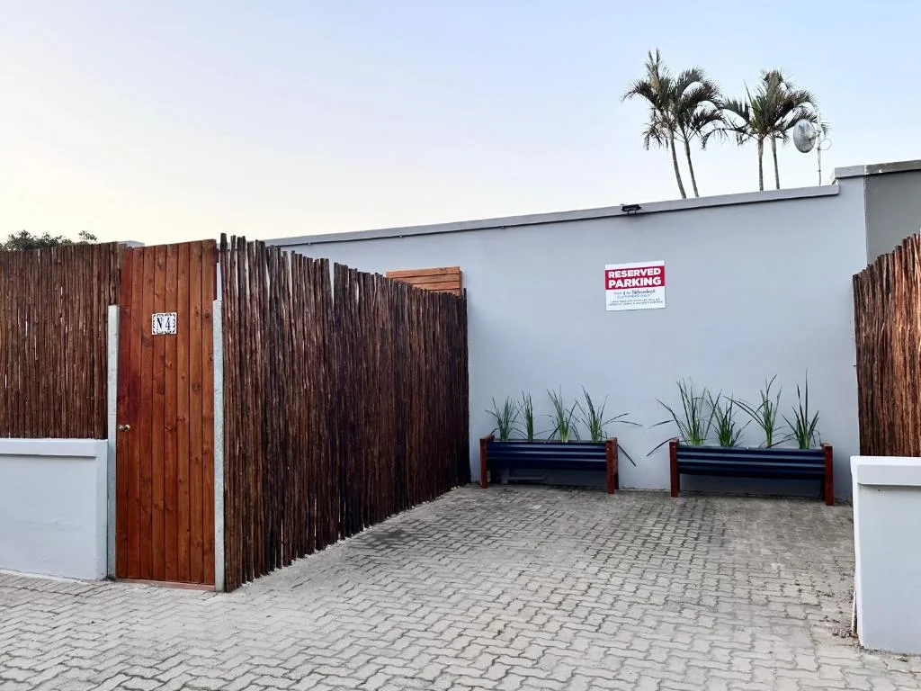 Modern white and timber building facade with wooden gate entrance and driveway