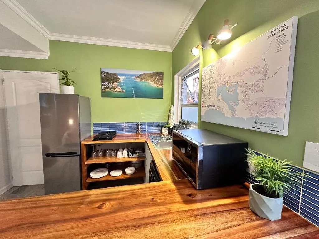 Modern kitchen with green walls, wooden counters, and stainless steel appliances