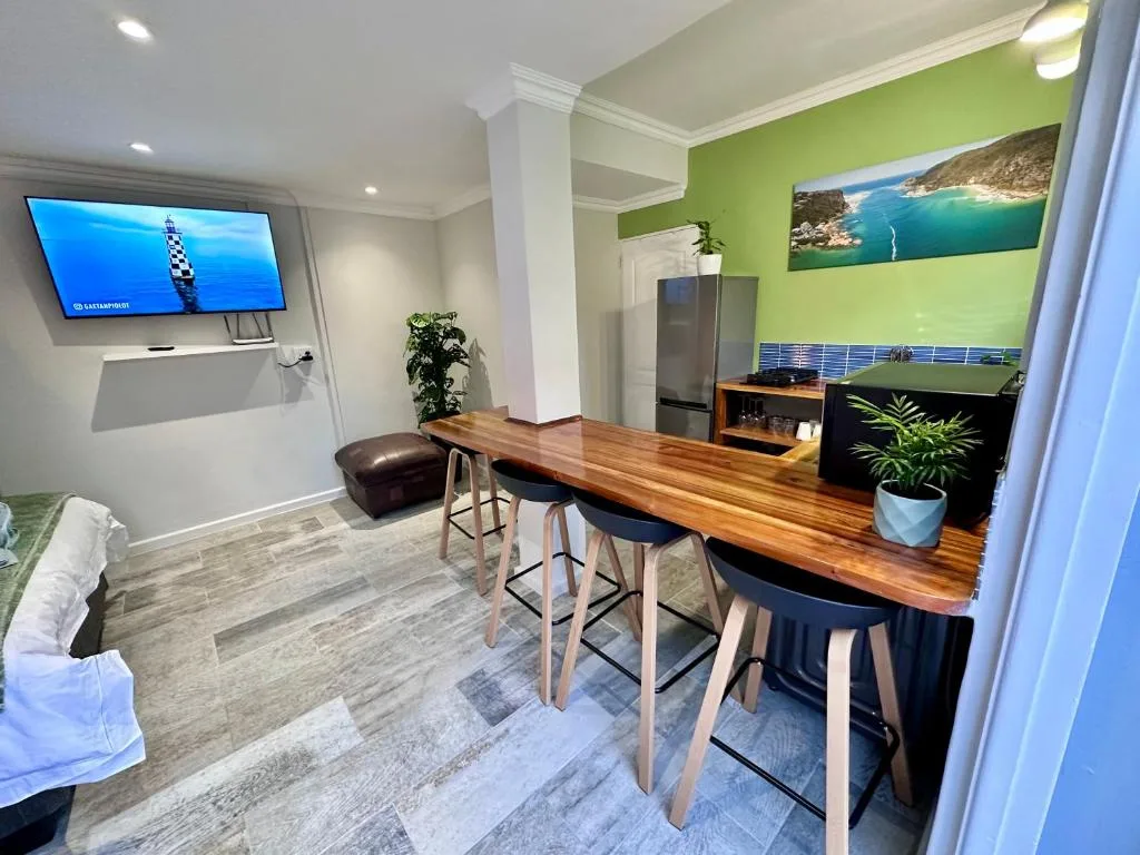 Modern open-plan lounge with wooden counter, bar seating, and wall-mounted TV