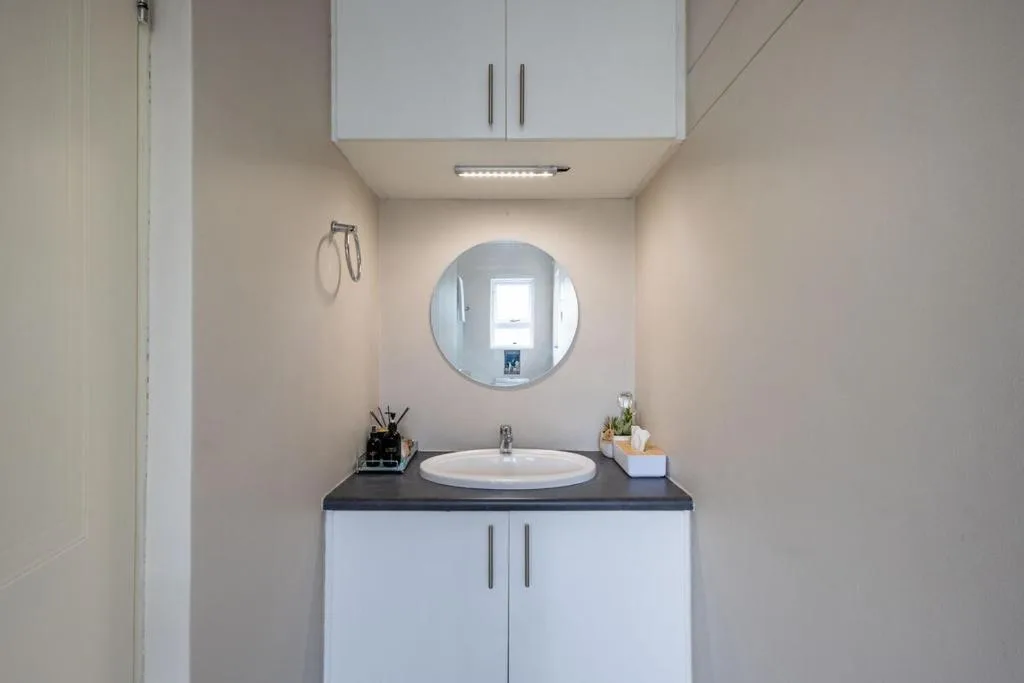 Modern bathroom vanity with round mirror and white cabinetry