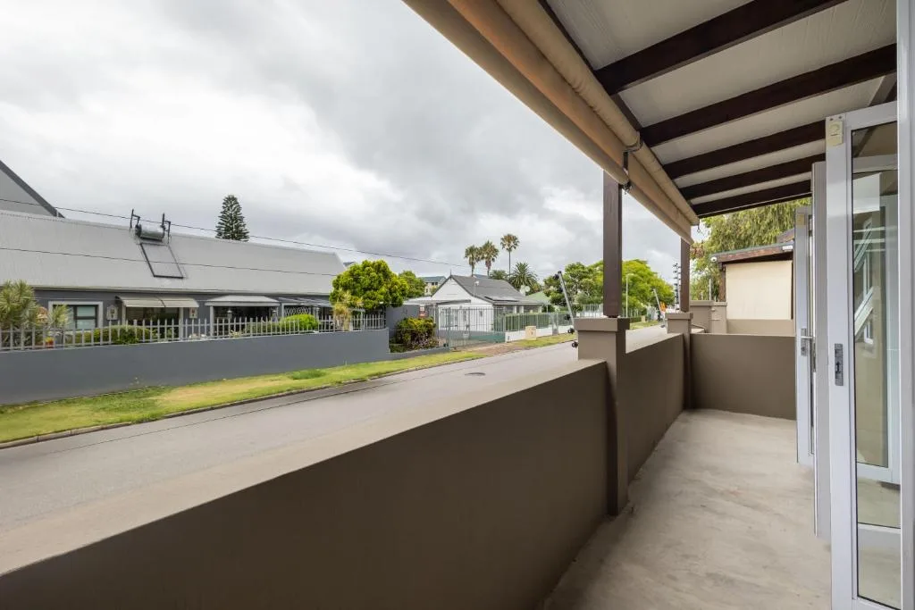 Covered patio overlooking residential street with green landscaping and homes
