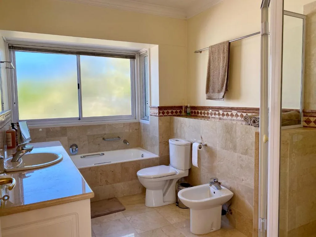 Spacious bathroom with bathtub, toilet, bidet, and double vanity sink