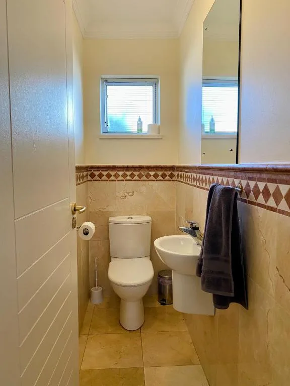 Compact bathroom with toilet, bidet, and window overlooking garden area