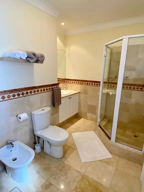 Bathroom with shower stall, toilet, vanity, and decorative tile trim