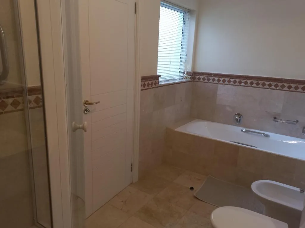 Spacious bathroom with bathtub, toilet, and window with blinds
