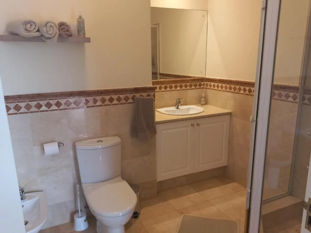 Spacious bathroom with toilet, vanity sink, and shower enclosure