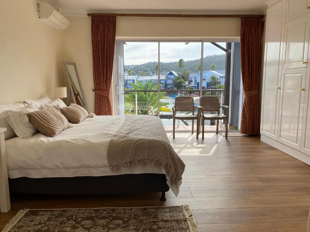 Spacious bedroom with bed, burgundy curtains, lagoon view through sliding doors