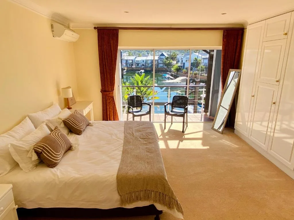 Bright bedroom with queen bed, deck access overlooking waterfront and pool area