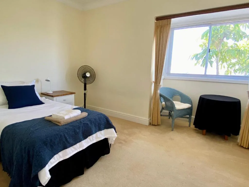 Bright bedroom with navy bedding, window view, and comfortable seating area