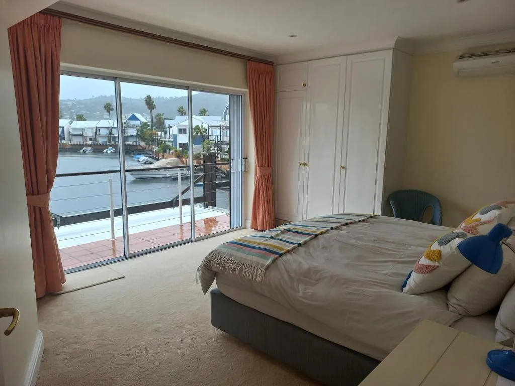 Spacious bedroom with bed, waterfront views through sliding glass doors