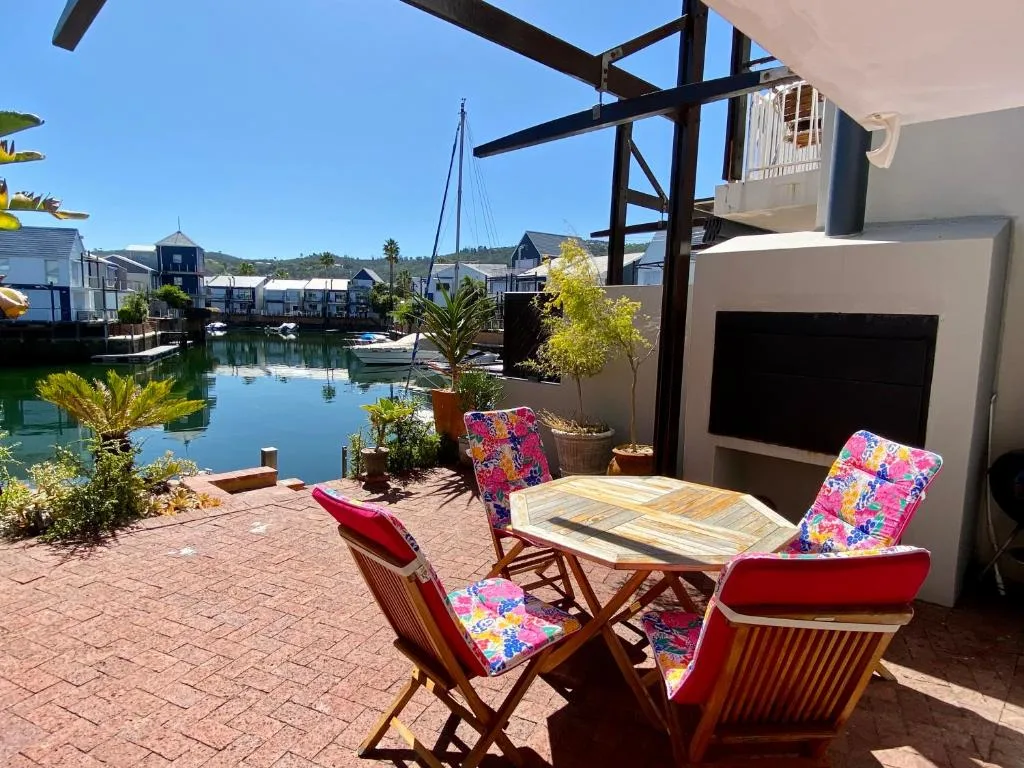 Waterfront patio with dining table, colorful cushioned chairs, and lagoon views
