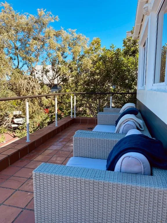 Spacious deck with rattan loungers overlooking leafy garden views