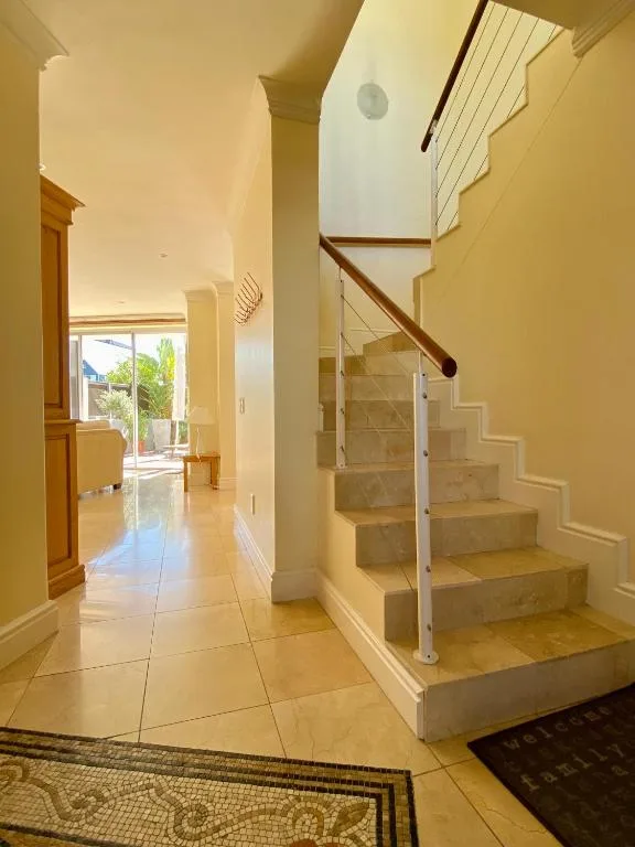 Bright hallway with staircase and open glass railing, leading to entrance