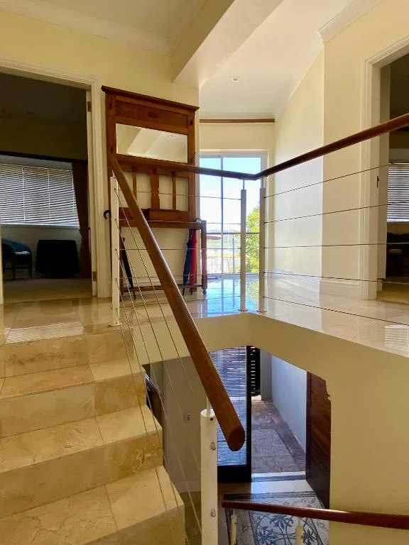 Modern wooden staircase with cable railing overlooking open-plan interior space