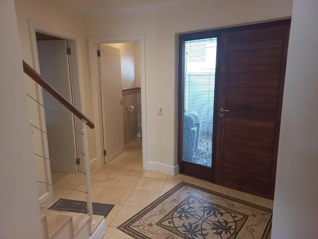 Hallway entrance with wooden door, staircase, and decorative floor mat