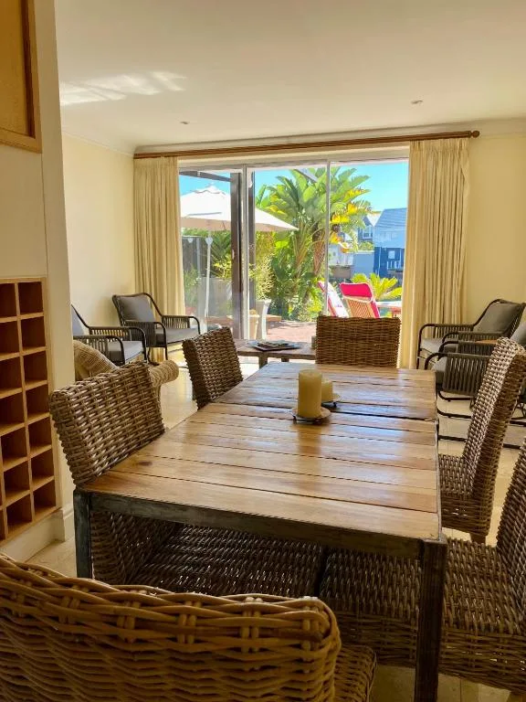 Bright dining room with wooden table and woven chairs overlooking garden