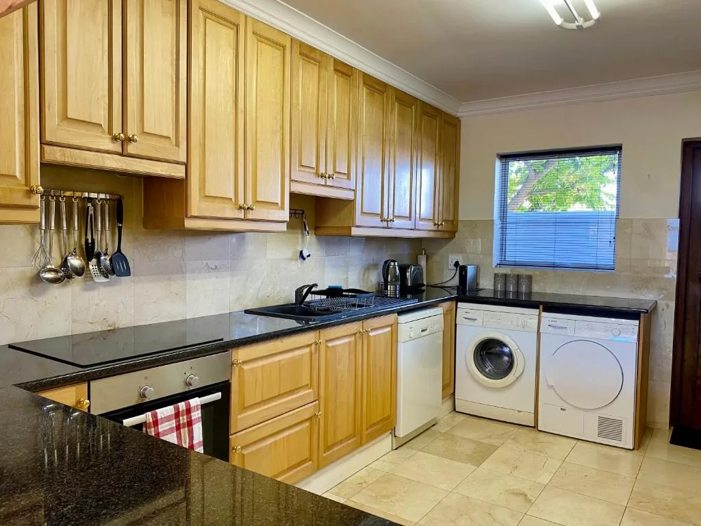 Spacious kitchen with wooden cabinetry, black granite countertops, and modern appliances