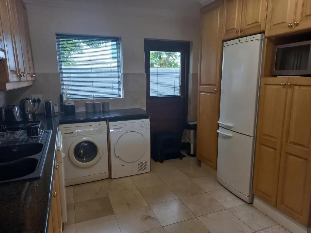 Spacious kitchen with washing machine, dryer, large fridge, and wooden cabinetry