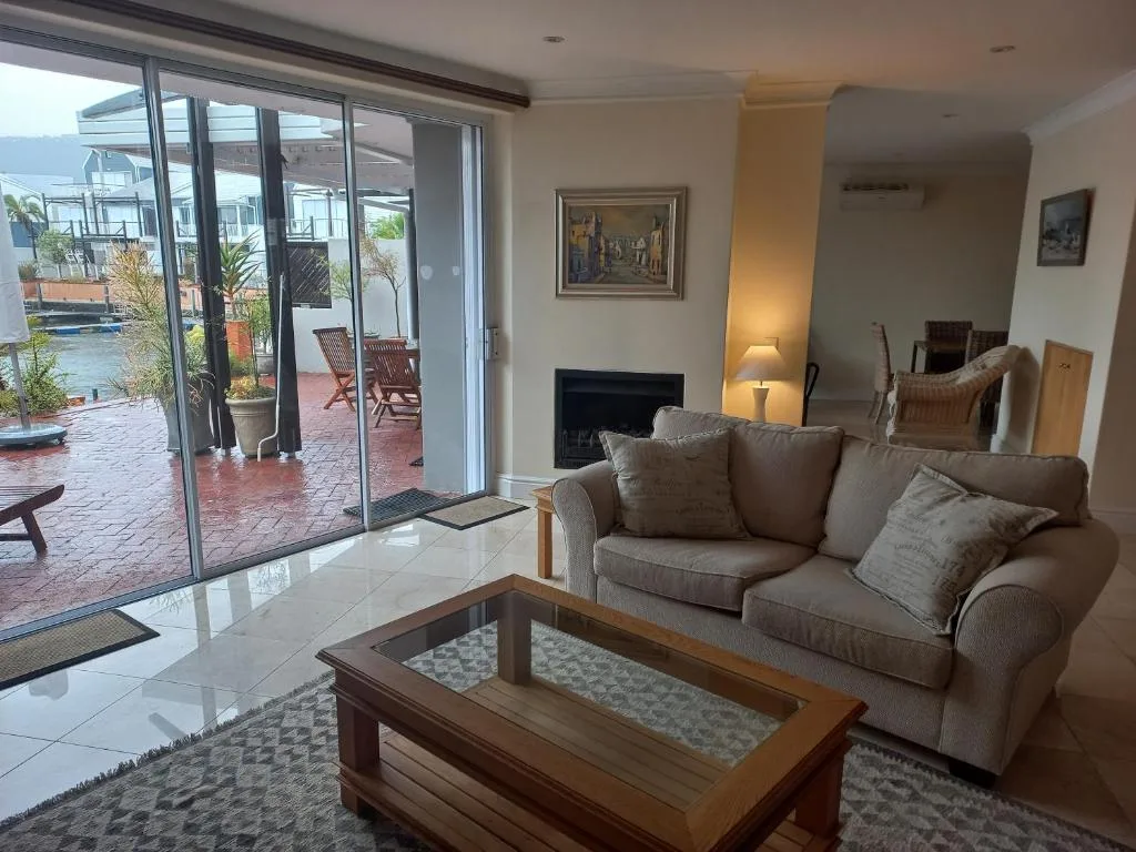 Spacious lounge with beige sofa, fireplace, and glass doors opening to deck
